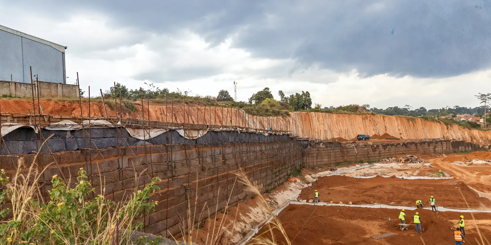 Deep excavation held by a reinforced retaining face, with the Tetrabuild crew working at the base