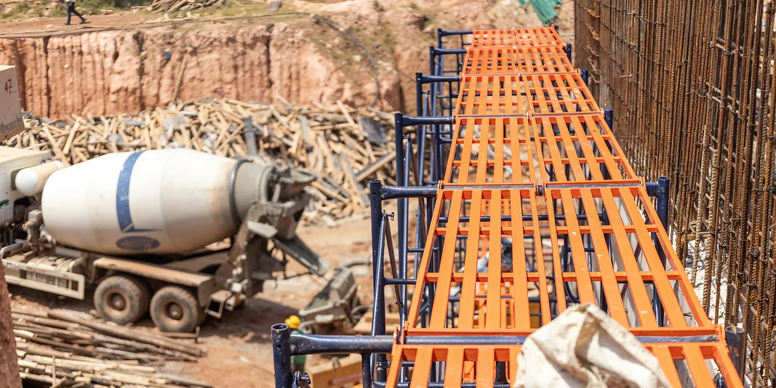 Orange formwork tables set out beside a concrete mixer truck on a Tetrabuild building site